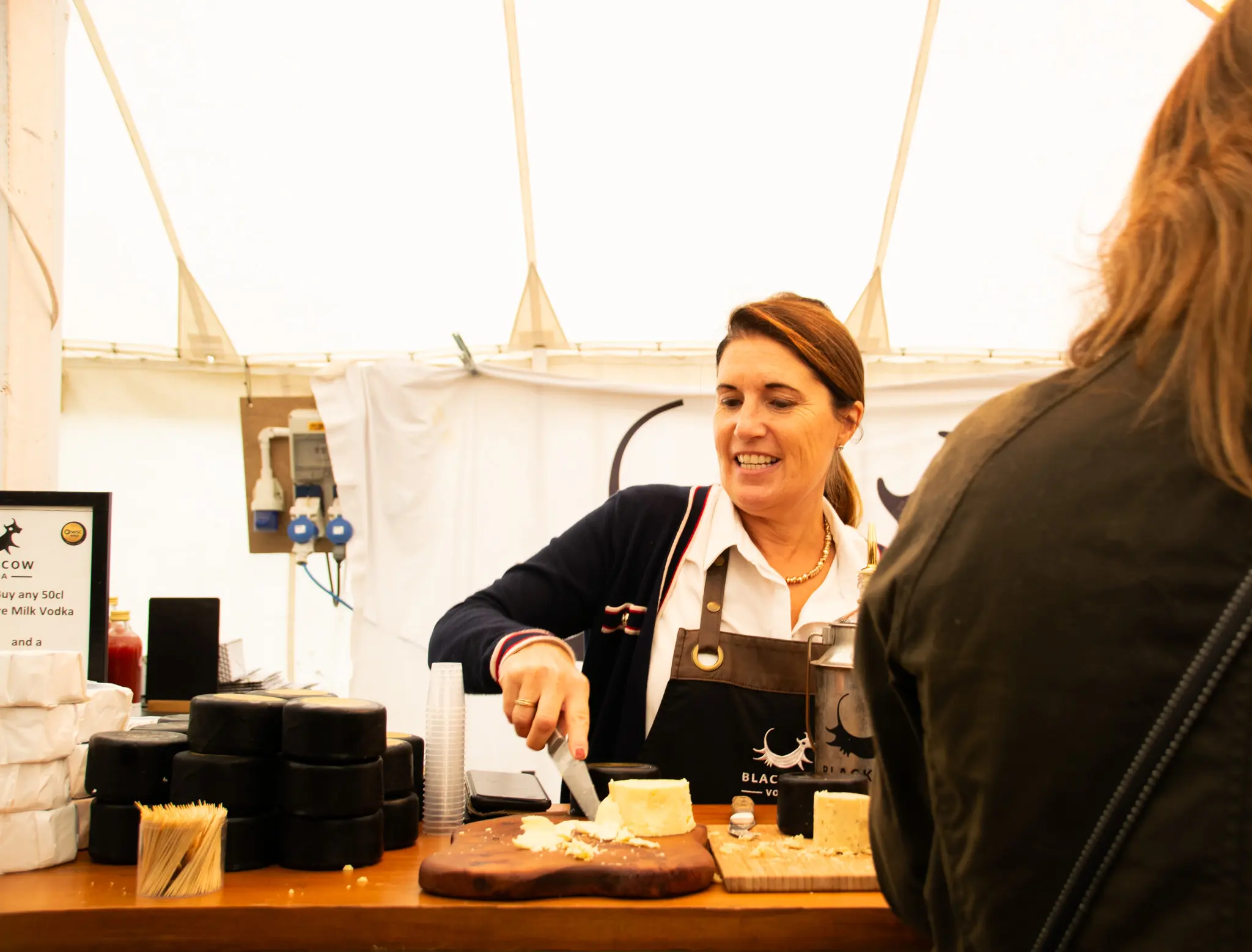 Woman slicing cheese at market stall