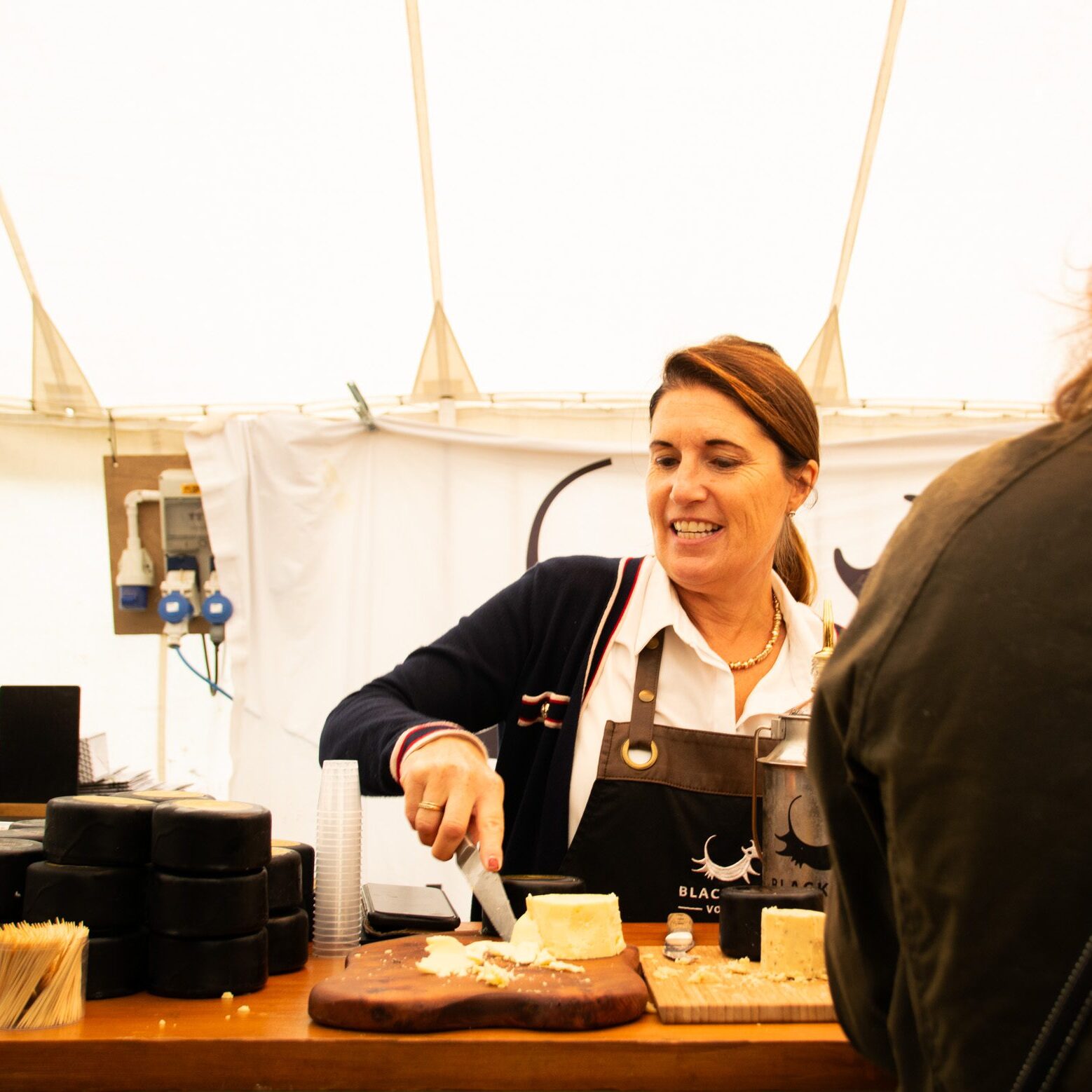 Woman slicing cheese at market stall